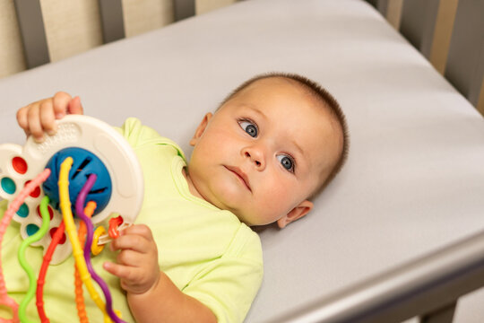 Baby Boy Holding Colorful Sensory Toy On Changing Mat