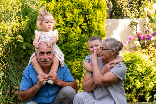 Grandparents Playing Affectionately With Grandchildren in Sunny Garden