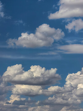 Layered White Cumulus Clouds Across Clear Blue Summer Sky