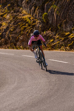 Dynamic vertical front-facing view of a female cyclist leaning into a curve at high speed on a road bike&mdash;in an aerodynamic position&mdash;on a mountain road on the Costa Brava, Spain.