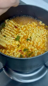 Cooking delicious and steaming hot Korean instant ramen noodles in a pot