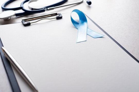 Stethoscope and Blue Prostate Cancer Awareness Ribbon on Clipboard in Medical Office