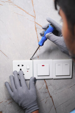 Man works on electrical switchboard using screwdriver in indoor setting