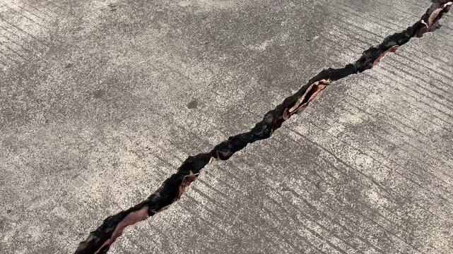 Deep diagonal crack on broken concrete road pavement texture
