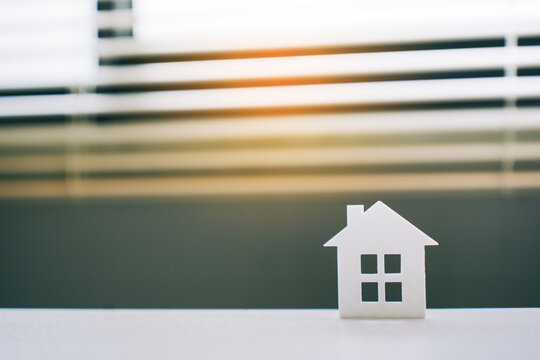 White house model figurine placed on desk with blurred window background for real estate concept and mortgage investment planning for home ownership