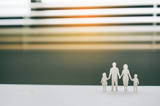 Family  figures holding hands as symbol of protection and unity on bright window background, concept of home insurance and financial planning
