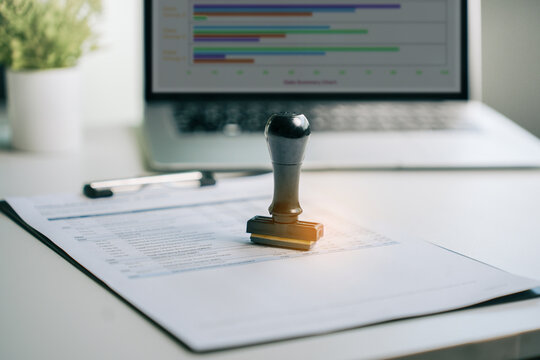 Business rubber stamp placed on financial report document with laptop computer in modern office for professional audit compliance and corporate document verification, conceptual business success