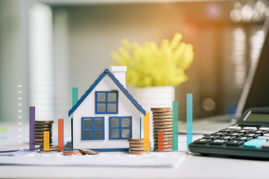 Real estate investment growth with house model and coin stacks showing financial market bar chart on office desk for mortgage planning and property business strategy