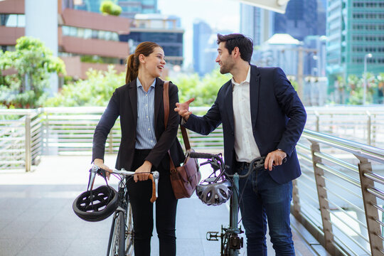 Business people pushing bicycles and talking on city skywalk bridge