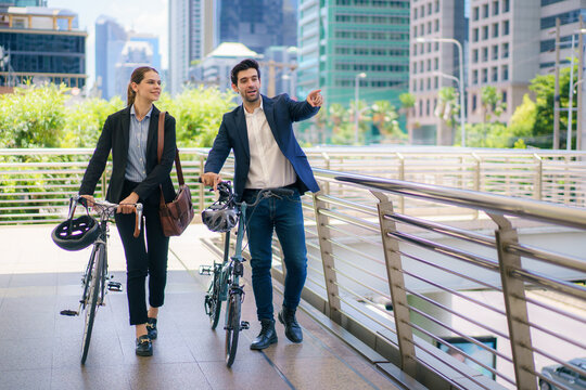 Business people pushing bicycles and talking on city skywalk bridge