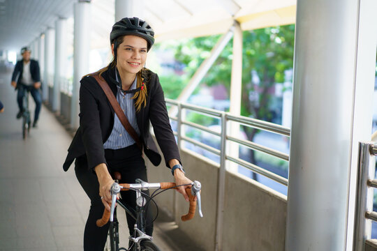 Businesswoman riding folding bicycle on city skywalk in morning commute