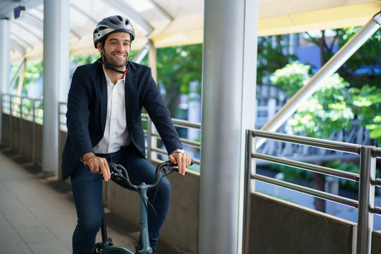 Businessman wearing helmet riding bicycle on city skywalk bridge