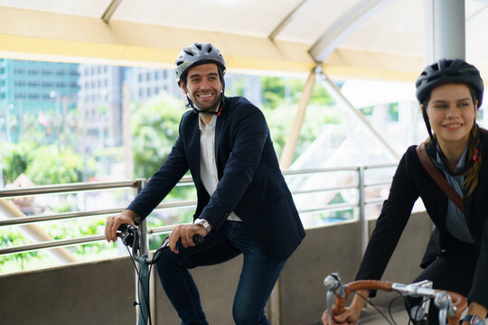 Business people wearing helmets riding bicycles on city skywalk