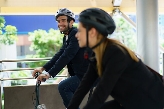 Business people wearing helmets riding bicycles on city skywalk