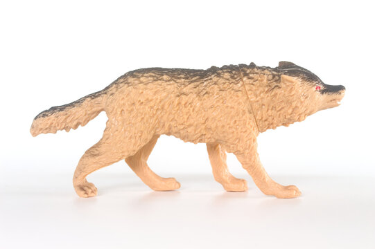 Toy wolf figurine side profile walking on white background