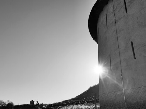 Black and white low angle view of a historic defense tower in Bellinzona with starburst sunlight
