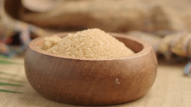 Brown sugar in a wooden bowl on a table with a textured background
