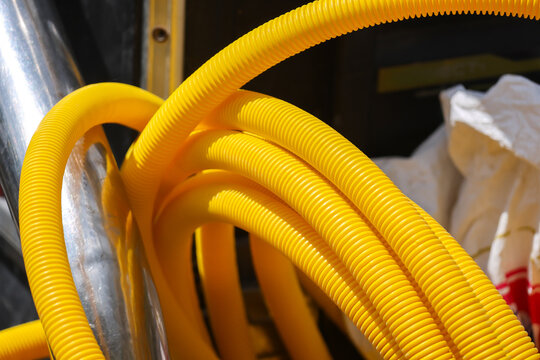 Yellow corrugated plastic hose coil beside reflective insulation in industrial service area, showing flexible tubing, protective material, utility equipment, and vivid color detail