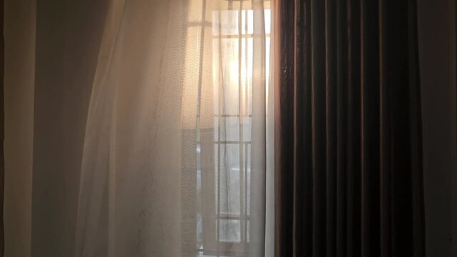 window with curtainsSoft light filters through sheer curtain. Dark drapes frame the window's edge. Warm glow suggests evening or early morning. Curtain sways gently with unseen breeze. Cozy, tranquil 