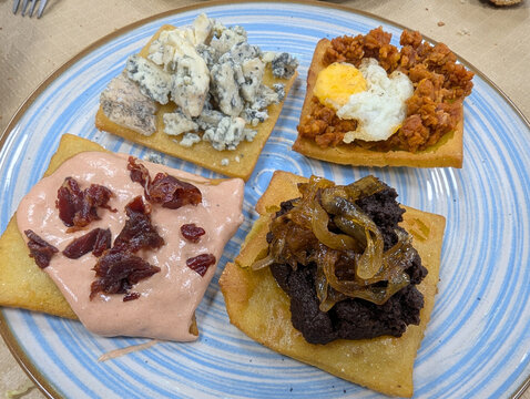 Assorted corn tortos with blood sausage, spicy minced pork, Cabrales blue cheese, and fried egg, traditional Asturian appetizer, Nava, Asturias, Comarca de la Sidra, Spain
