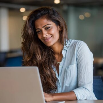 Beautiful businesswoman laughing while working on a laptop computer in a modern office space