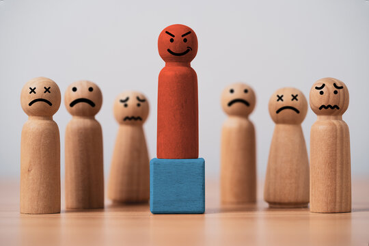 Toxic leadership and workplace bullying concept with a red wooden figure standing above distressed employees symbolizing abusive management to make fear by power harassment and toxic culture.