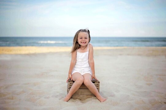 Happy young girl with a missing tooth sitting on a beach