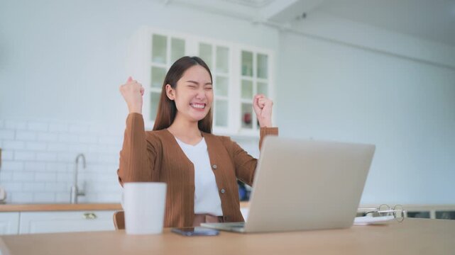 Funny euphoric young asian woman celebrating winning or getting ecommerce shopping offer on computer laptop. Excited happy girl winner looking at notebook celebrating success