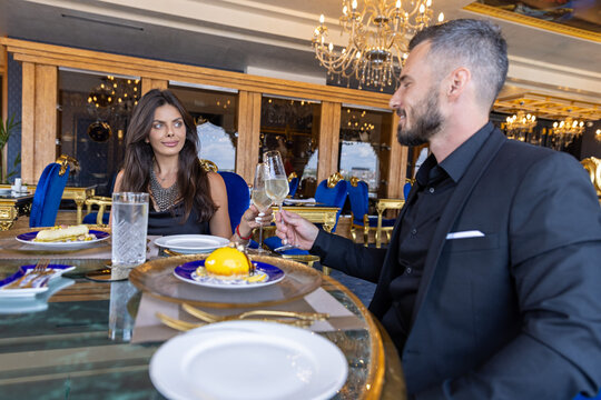 Wealthy couple toasting with champagne during fine dining dinner