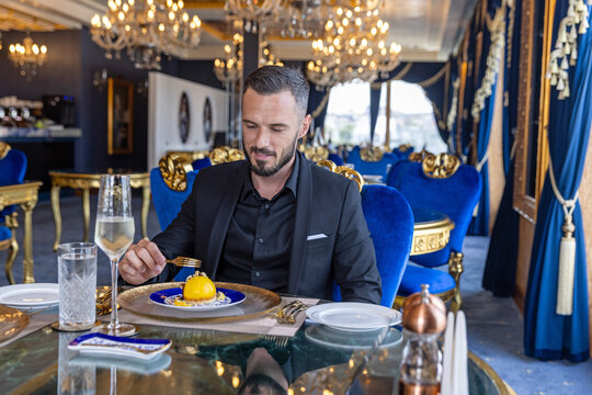 Handsome elegant man in suit eating dessert at luxury restaurant