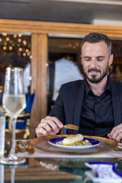 Elegant man in black suit tasting gourmet dessert at luxury restaurant