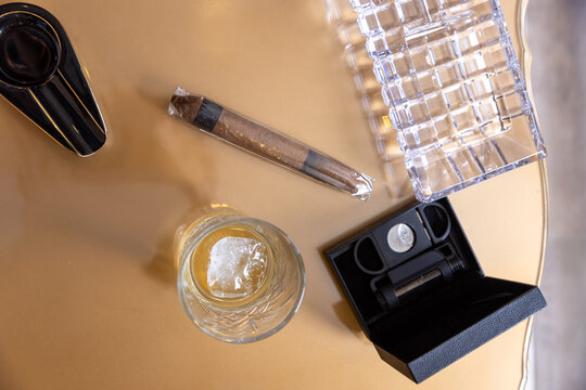 High angle view of cigar whiskey glass and cutter on table