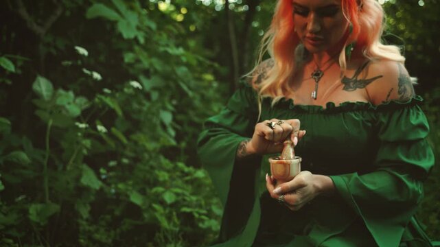 fantasy woman herbalist healer sitting at table on green grass summer garden, gothic detail glass, candles forest. elf girl holds stone mortar in hands creating powder healing potion, grinds spices 