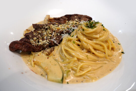 Italian gourmet steak cream spaghetti garnished with herbs, close up look