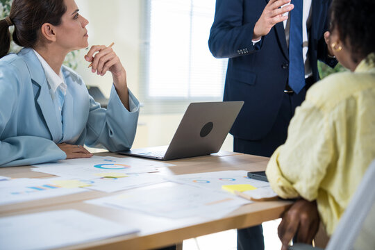 Businesspeople executive standing and using hand gestures to explain a business strategy to his colleagues during a collaborative meeting in office.