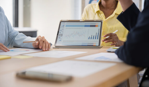 Business team discussing financial charts and data on a digital tablet during a meeting in a modern office corporate strategy, and teamwork.