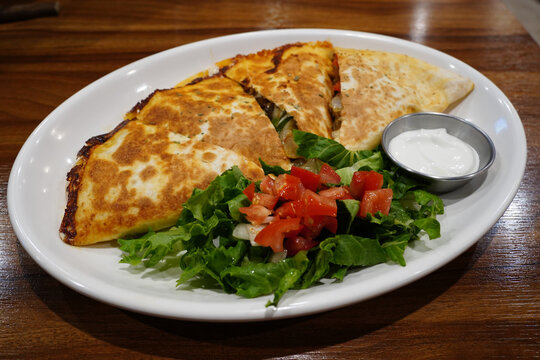 Mexican chicken quesadilla triangles served with fresh salad and sour cream