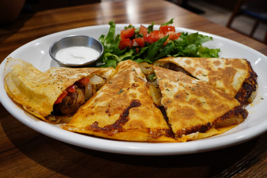 Mexican chicken quesadilla triangles served with fresh salad and sour cream
