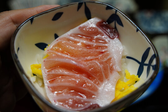 Premium marbled tuna belly sunazuri sashimi on a mini rice bowl held in a hand