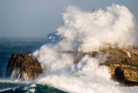 Massive storm wave crashing over Mouro Island Lighthouse in Santander, Spain