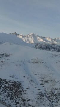 Drone footage of wide winter landscape in Chunkurchak Valley, Chuy Region, Kyrgyzstan, with snow covered ridges and peaks under soft morning light