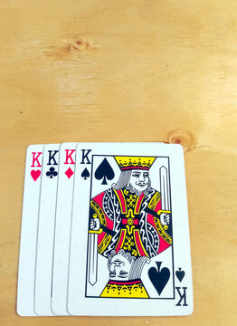 Four King Playing Cards Fan Out on Wooden Table
Four king playing cards are displayed fanned out on a smooth wooden table surface.