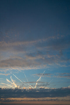 Dramatic Sunset Sky with Clouds and Airplane Contrails