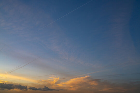Dramatic Sunset Sky with Clouds and Airplane Contrails