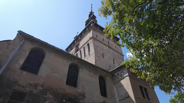 Historic Sighisoara Clock Tower and old architecture framed by trees in Transylvania Romania