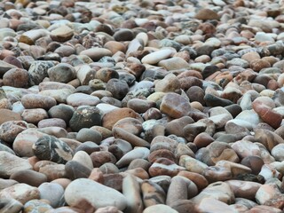 Close-Up View of Diverse Pebbles and Stones in Various Colors and Shapes on a Textured Surface © George C