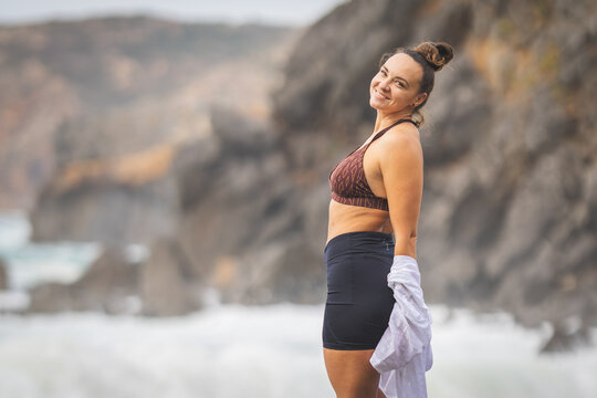 Woman enjoying a day at the beach near rocky cliffs with ocean waves in the background