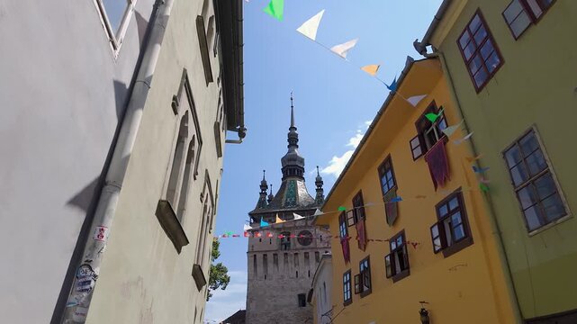 Sighisoara Clock Tower framed by colorful buildings and bunting in Transylvania Romania