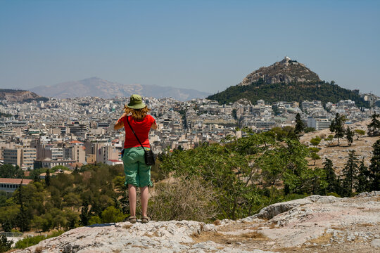 Tourist standing on Filopappou Hill observing Mount Lycabettus and Athens cityscape