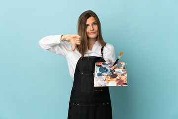 Young artist Slovak woman isolated on blue background showing thumb down with negative expression © luismolinero